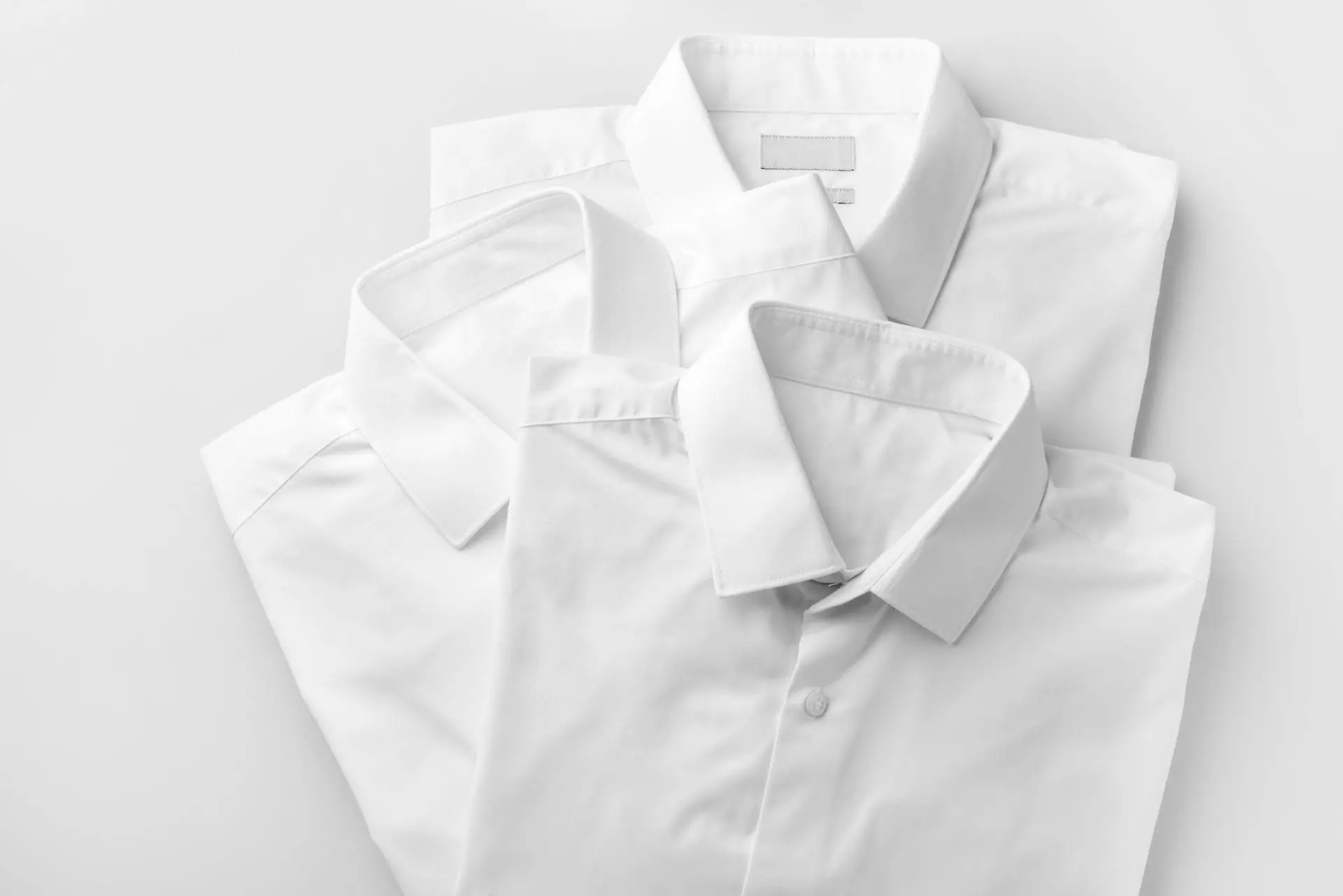 A rack of white and blue shirts hanging in front of a window.
